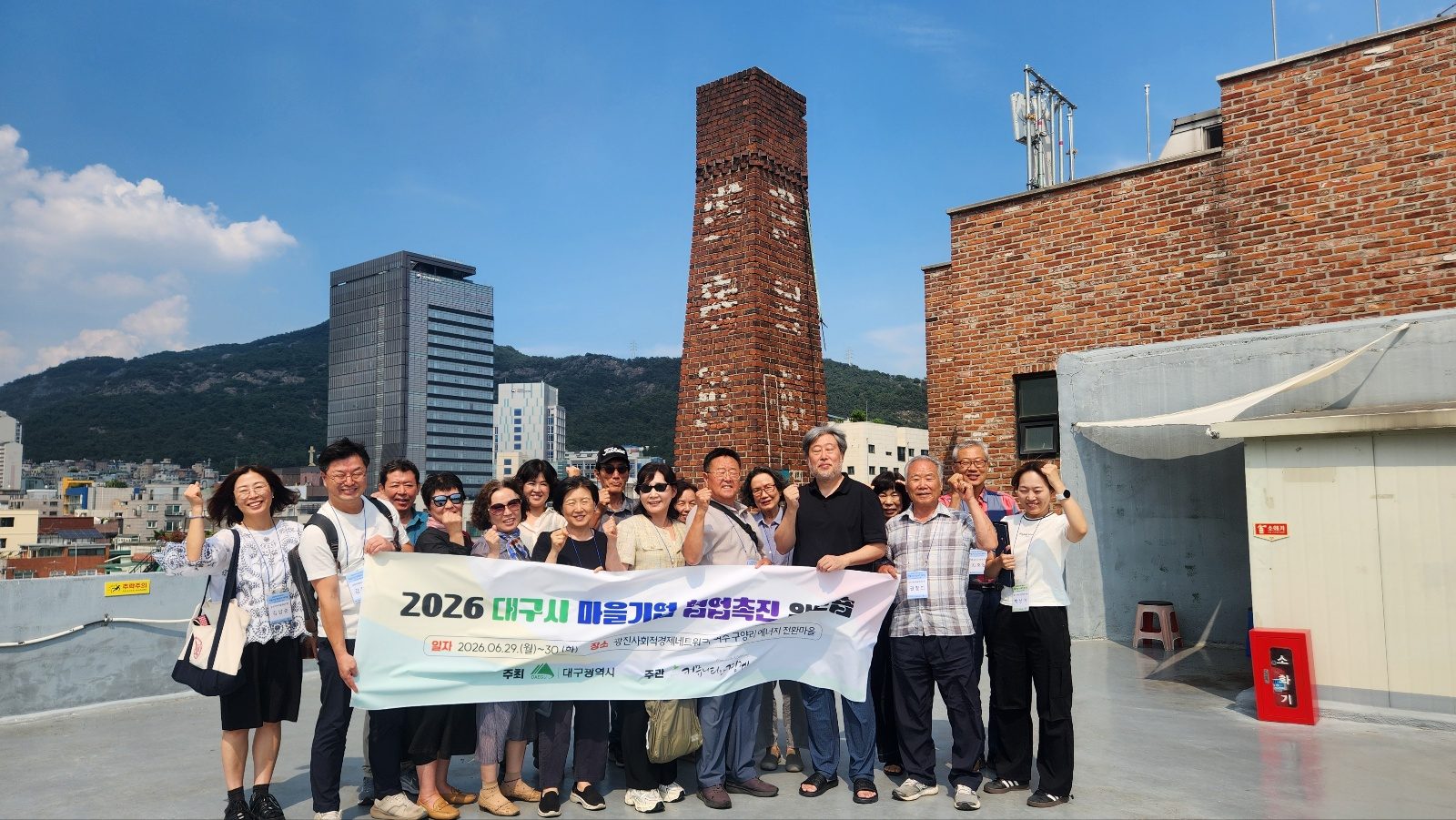 광사넷 옥상에서 대구마을기업협의회 탐방단과 광사넷 관계자가 현수막을 들고 주먹을 쥔 단체사진